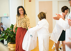 medical student smiles as she dons her white coat