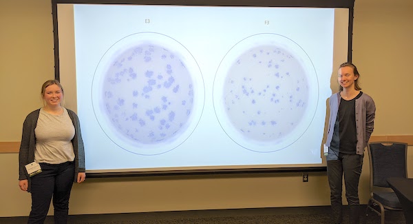 Hannah Despres and Madaline Schmidt next to large screen showing cells