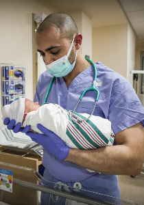 Kiro Solomon holding a newborn in the nursery