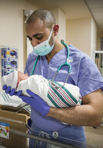 Kiro Solomon holding a newborn in the nursery Kiro Solomon holding a newborn in the nursery