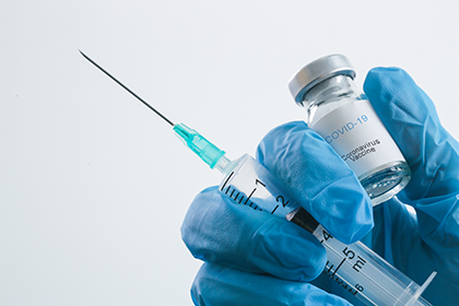 gloved hand holding syringe and covid-19 vaccine vial