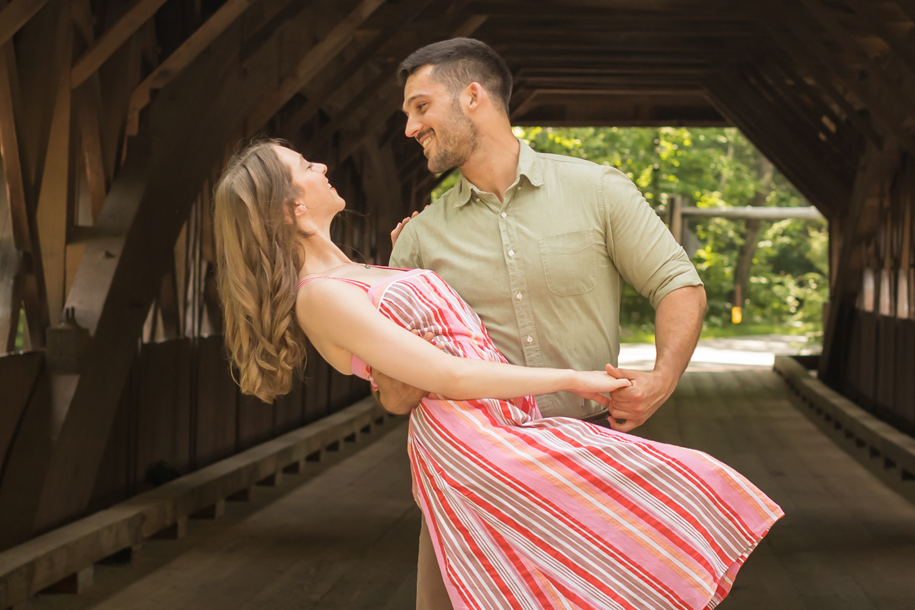 a woman and man dancing in a covered bridge