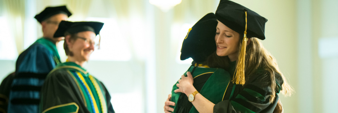 Female appearing graduate hugs an LCOM Faculty member at ceremony